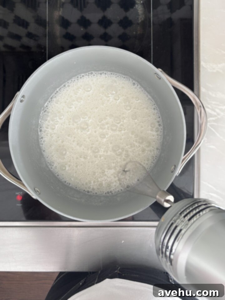 Effortless 7-Minute Frosting 5 A hand mixer whipping egg whites and sugar in a pot directly on a stovetop.