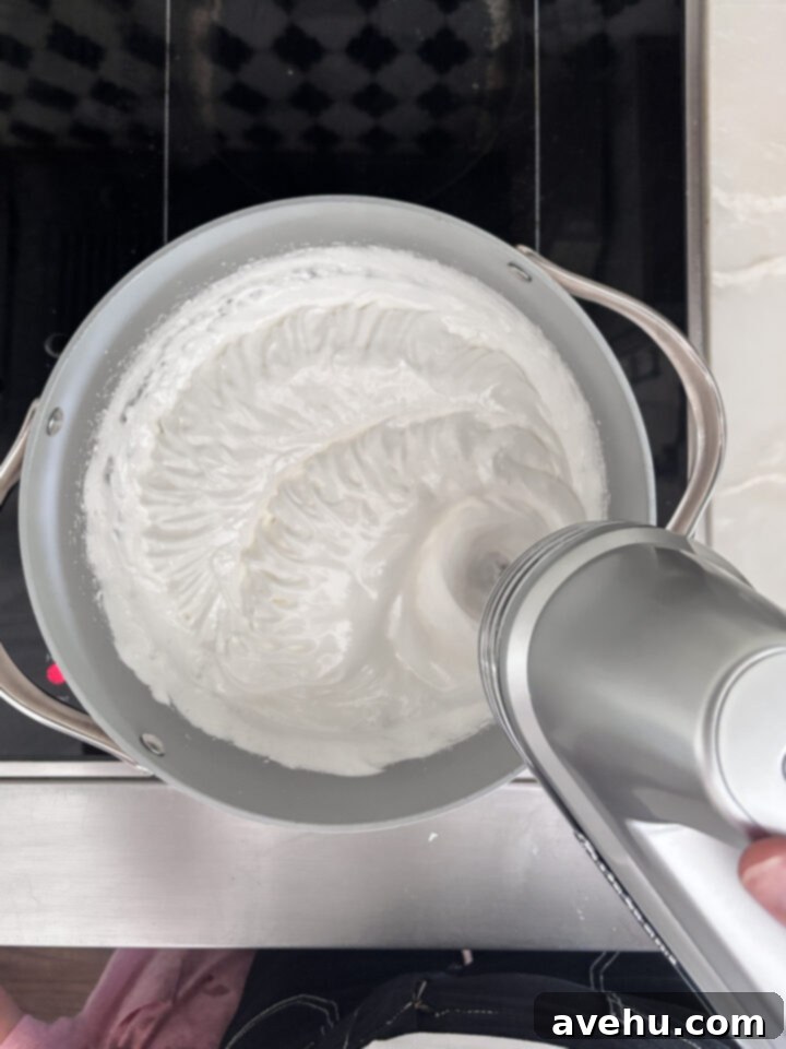 Effortless 7-Minute Frosting 6 7 minute frosting being whipped in a pot, showing increasing volume and thickness.