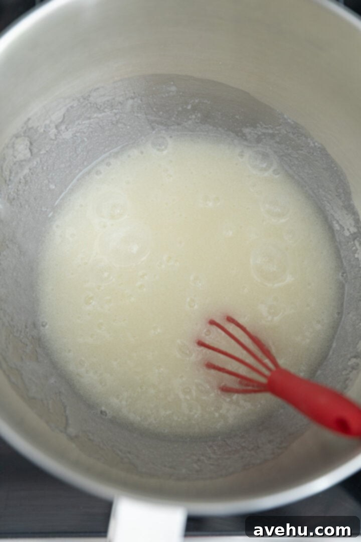 Seriously Addictive Swiss Meringue Buttercream 11 Egg whites and sugar foaming in a mixing bowl.