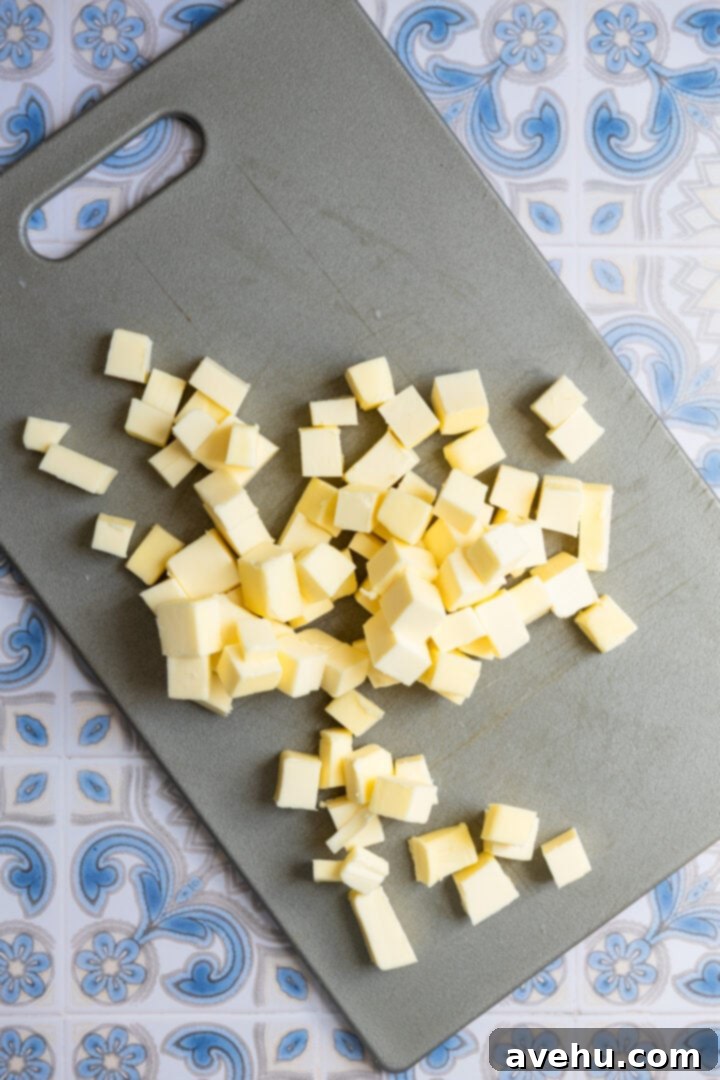 Seriously Addictive Swiss Meringue Buttercream 13 Diced butter on a gray cutting board.