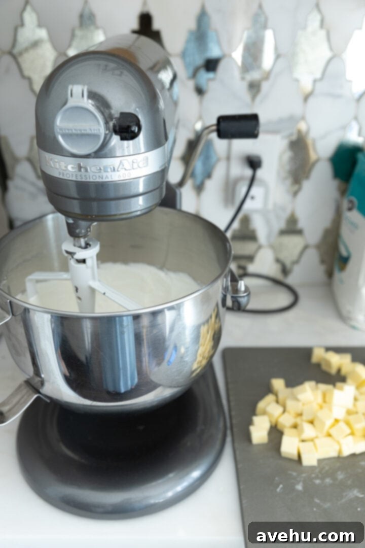 Seriously Addictive Swiss Meringue Buttercream 16 Meringue in a mixing bowl next to diced butter.