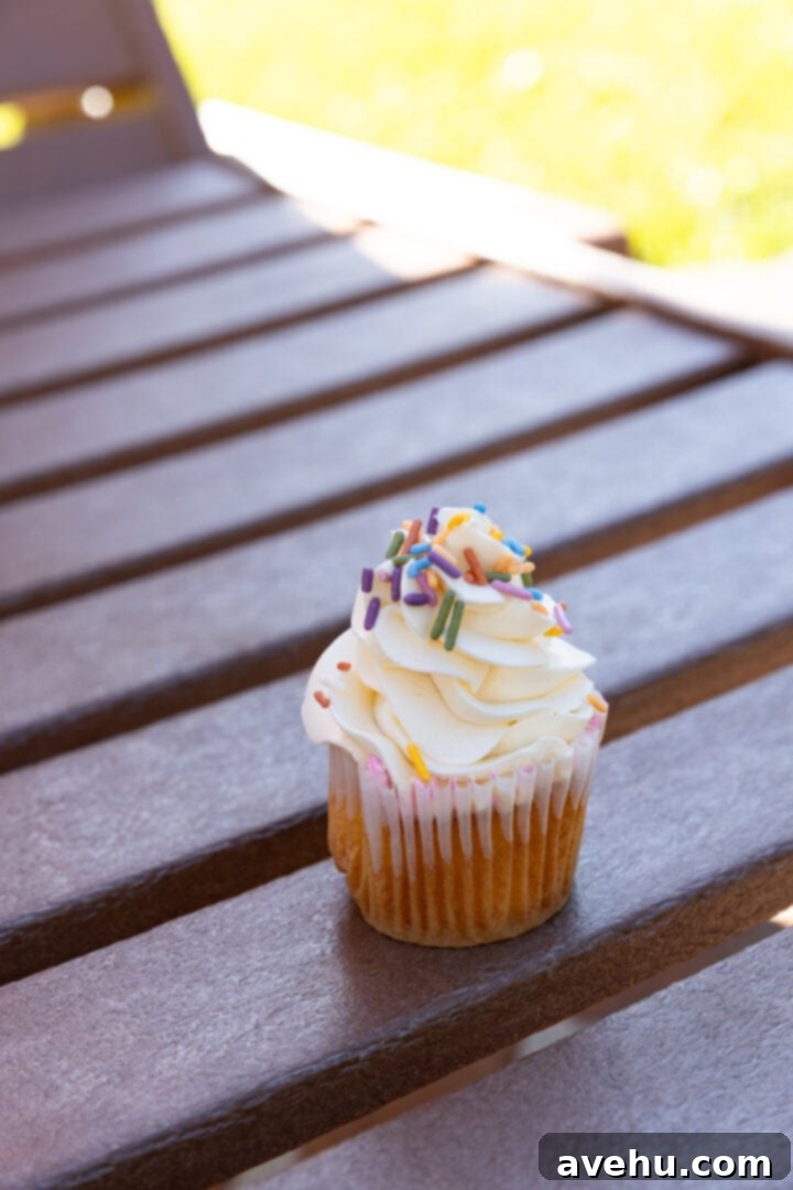 Seriously Addictive Swiss Meringue Buttercream 4 A vanilla cupcake and frosting on wooden slats.