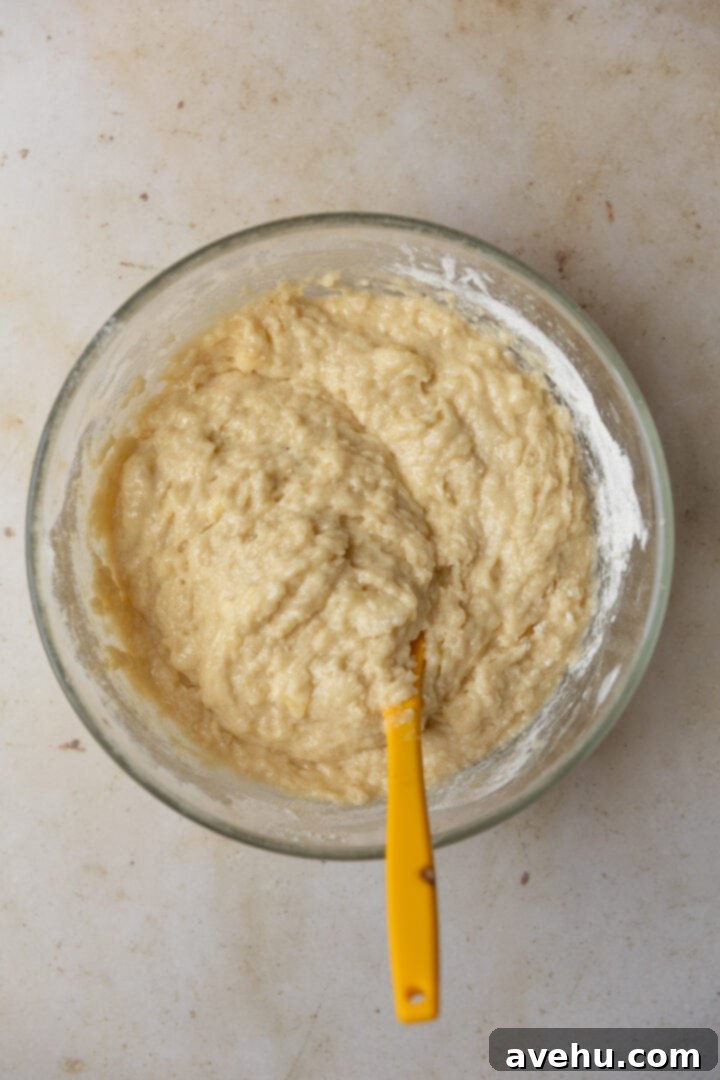 Perfectly Moist Bakery-Style Banana Muffins 6 Thick, lumpy banana muffin batter in a glass bowl after dry and wet ingredients have been gently folded together.