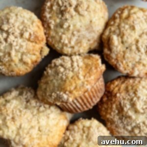 Perfectly Moist Bakery-Style Banana Muffins 10 Bakery-style banana muffins with a golden, crunchy streusel topping clustered together.