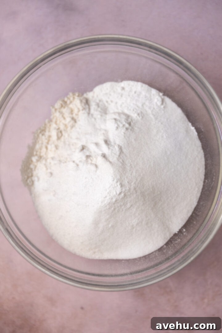 Crave-Worthy Blackberry Streusel Muffins 5 Dry ingredients for blackberry muffins in a glass bowl, including flour, sugar, baking powder, baking soda, and salt.