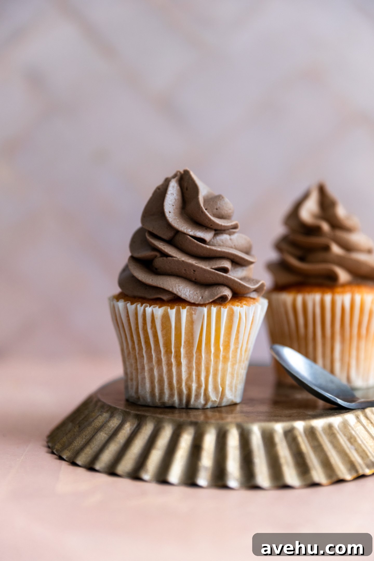 Decadent Cocoa Swiss Meringue Buttercream 11 A vanilla cupcake expertly frosted with rich, fluffy chocolate Swiss meringue buttercream, presented on an inverted platter.
