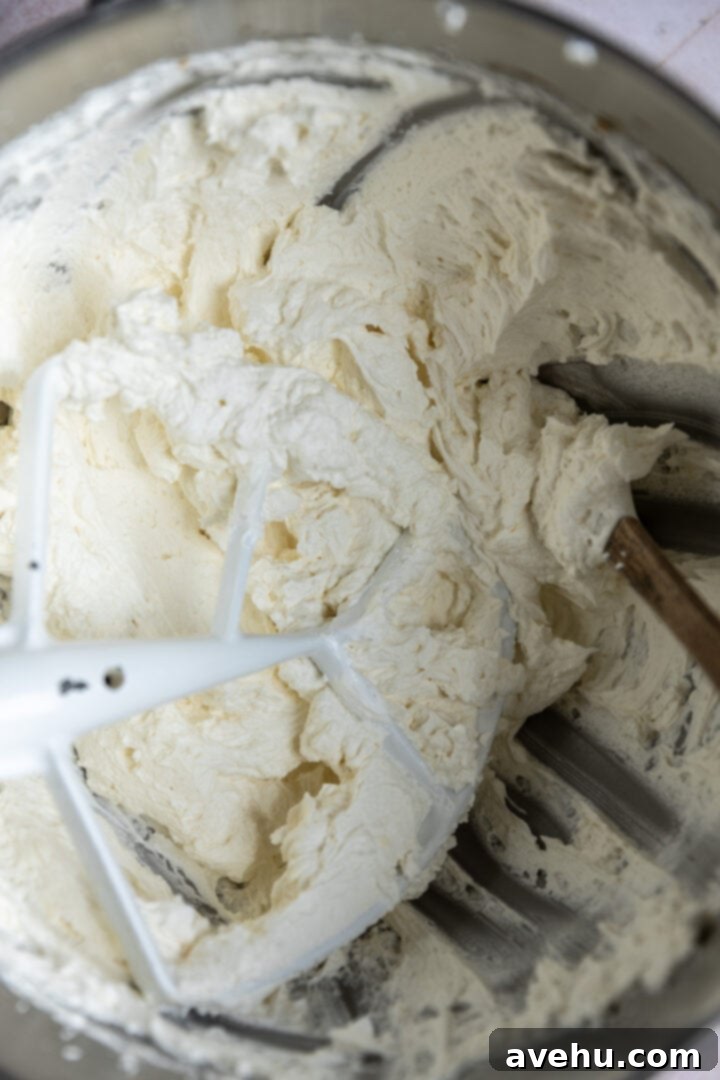 Decadent Cocoa Swiss Meringue Buttercream 8 Swiss meringue buttercream being mixed with a paddle attachment in a stand mixer after butter has been gradually incorporated.