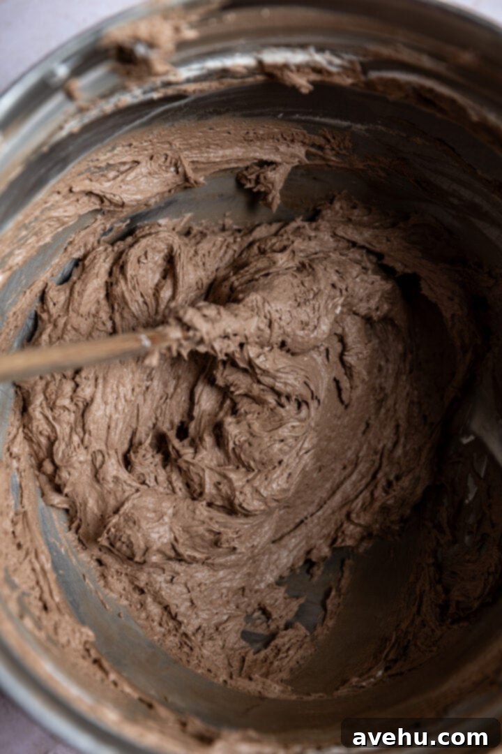 Decadent Cocoa Swiss Meringue Buttercream 10 Finished chocolate Swiss meringue buttercream in a mixing bowl after flavoring, appearing perfectly smooth and glossy.