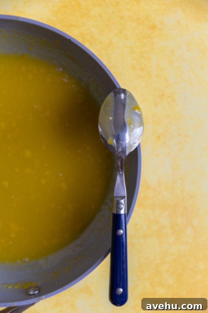 Zesty Lemon Curd Delight 4 A spoon resting over a pan of lemon curd.