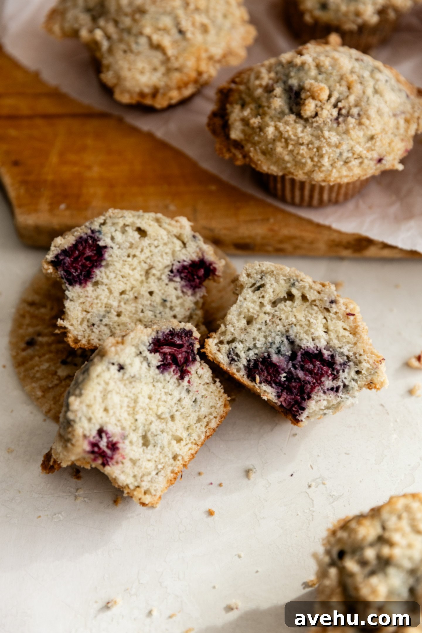 Ultimate Bakery Banana Blackberry Muffins 12 A banana blackberry muffin split in half, revealing blackberries distributed throughout the moist interior.