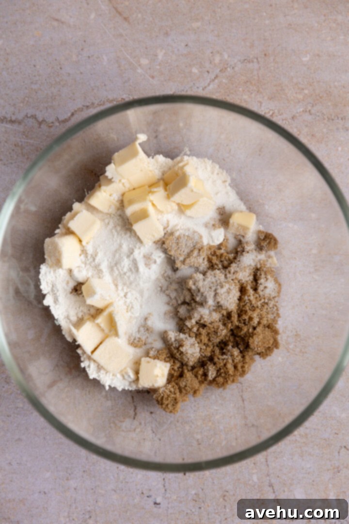 Ultimate Bakery Banana Blackberry Muffins 3 Streusel ingredients, including flour, sugar, brown sugar, salt, and diced cold butter, in a clear glass bowl.