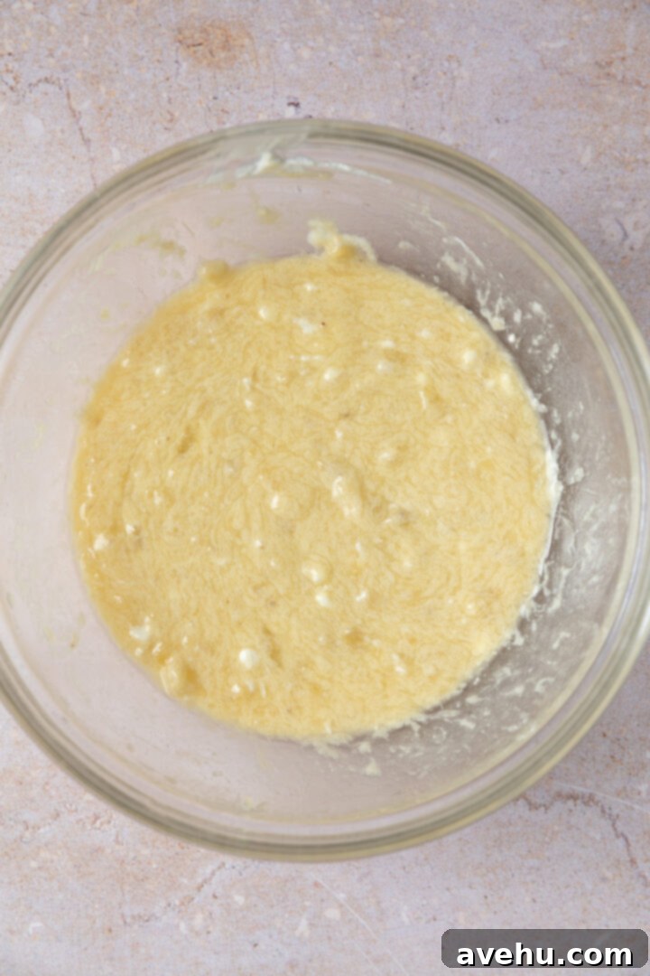 Ultimate Bakery Banana Blackberry Muffins 8 Liquid ingredients for banana blackberry muffins, including mashed bananas, melted butter, oil, Greek yogurt, eggs, and vanilla extract.