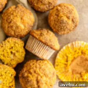 Bakery-Fresh Moist Pumpkin Banana Muffins 11 A cluster of freshly baked banana pumpkin muffins, golden brown with a shimmering cinnamon-sugar topping, on a rustic surface.