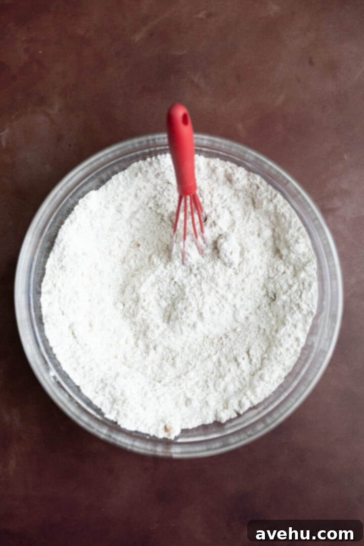 Bakery-Fresh Moist Pumpkin Banana Muffins 3 Dry ingredients for muffins, including flour, granulated sugar, and ground cinnamon, are perfectly measured in a clear glass bowl, ready for mixing.