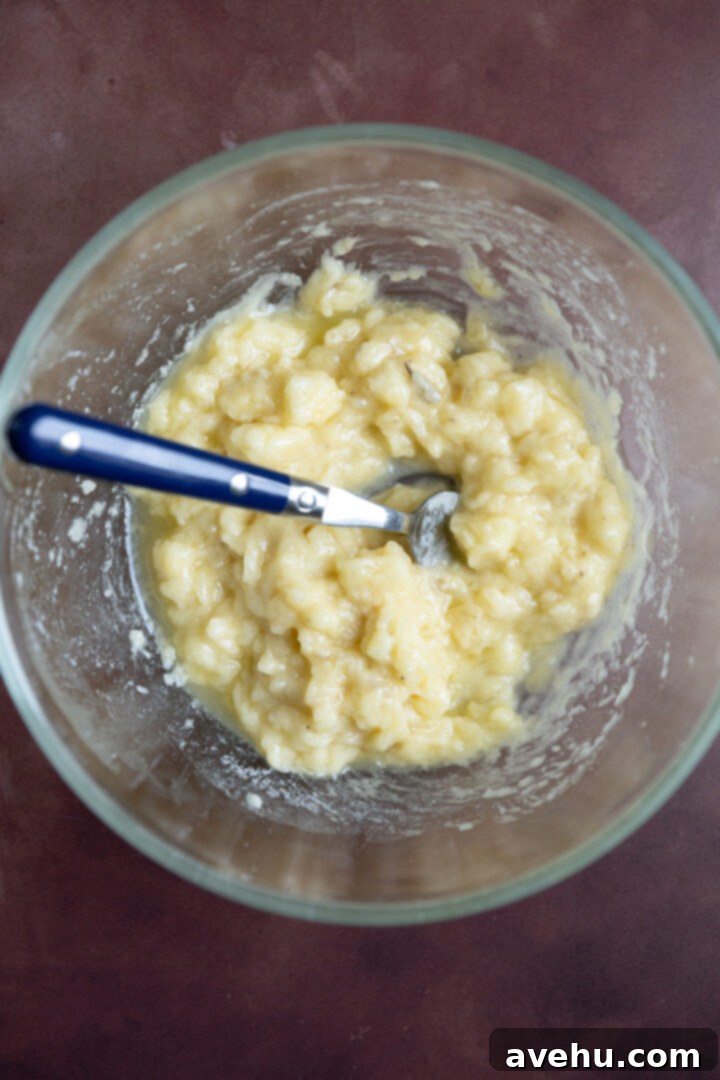 Bakery-Fresh Moist Pumpkin Banana Muffins 4 Perfectly mashed overripe bananas in a glass bowl, showcasing their lumpy texture, ready to be combined with other wet ingredients.
