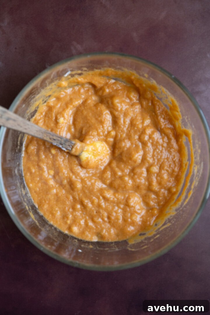 Bakery-Fresh Moist Pumpkin Banana Muffins 6 Bowl containing all liquid ingredients for pumpkin banana muffins, including oil, Greek yogurt, eggs, and maple syrup, thoroughly mixed.