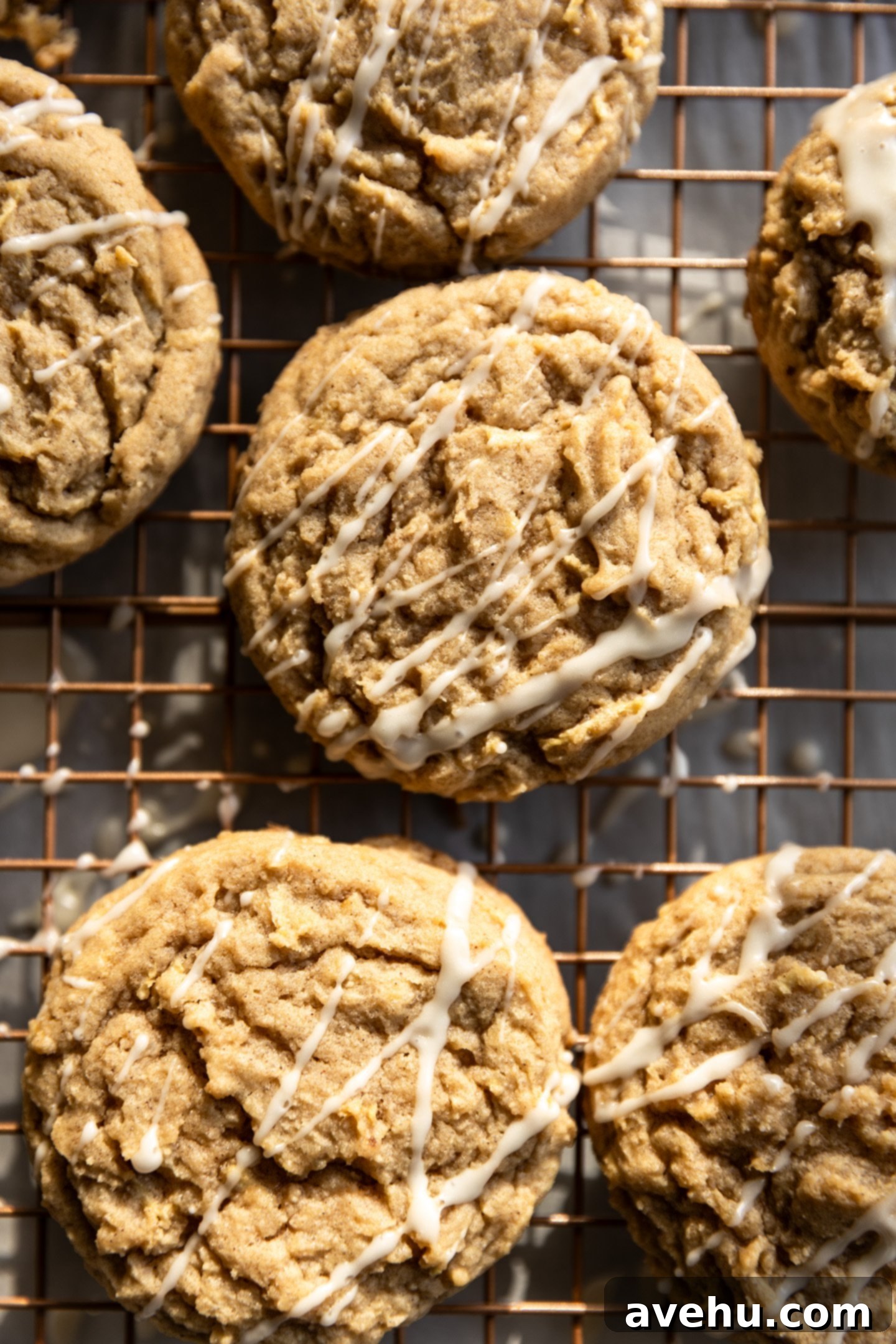 Maple-Glazed Autumn Apple Bites 2 Apple cookies with a white drizzle on a wire rack.