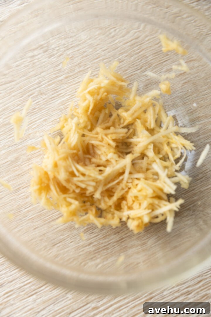 Maple-Glazed Autumn Apple Bites 4 Grated apple in a glass bowl.