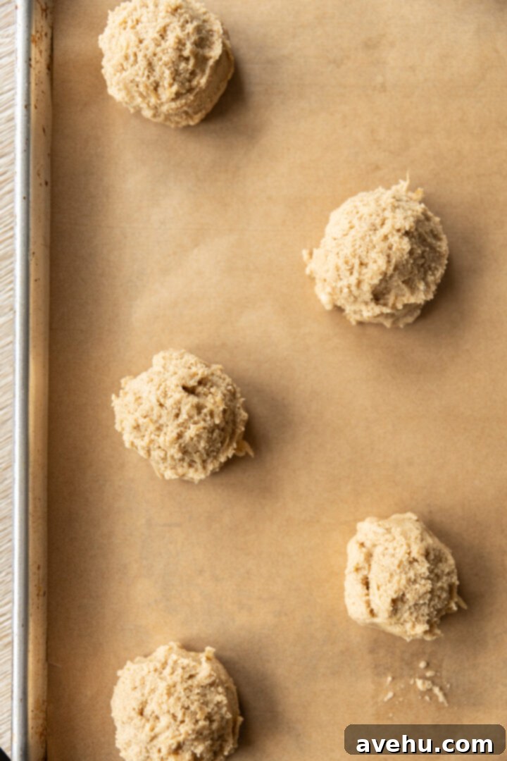 Maple-Glazed Autumn Apple Bites 7 Cookie dough balls on a cookie sheet.