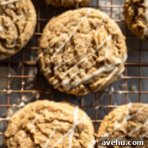 Maple-Glazed Autumn Apple Bites 9 Apple cookies with a white drizzle on a wire rack.