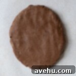 Zesty Orange Dark Chocolate Shortbread 4 A disk of chocolate shortbread cookie dough wrapped in parchment paper, ready for chilling.