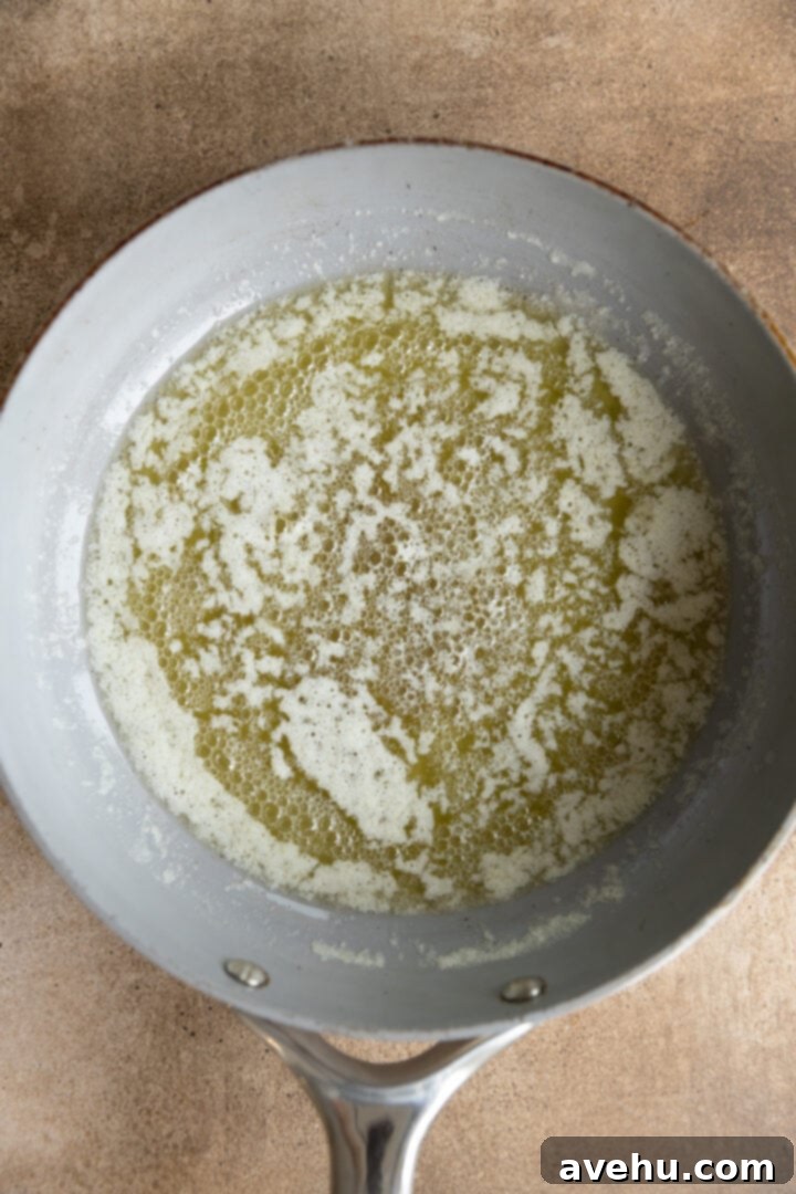 Your Ultimate Brown Butter Frosting 5 Yellow melted butter shimmering in a saucepan, with milk solids beginning to separate and sink.