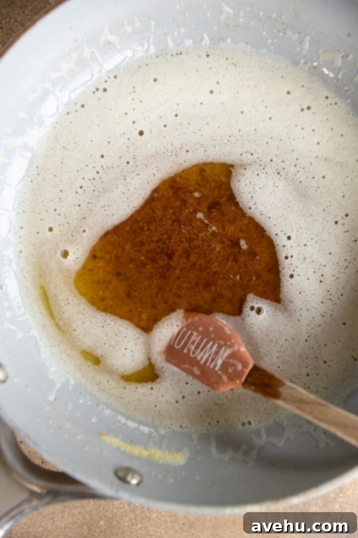 Your Ultimate Brown Butter Frosting 6 Perfectly browned butter in a saucepan with a spatula, showing rich amber color and visible flecks.