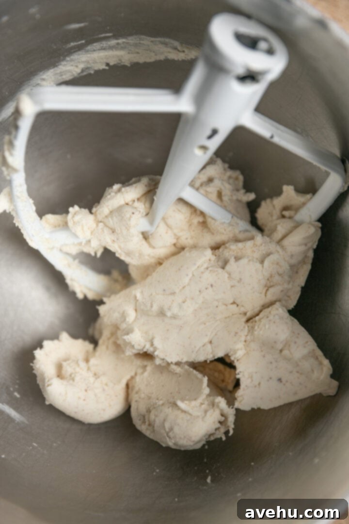 Your Ultimate Brown Butter Frosting 9 Powdered sugar and softened brown butter being creamed together in a mixer, forming clumps.