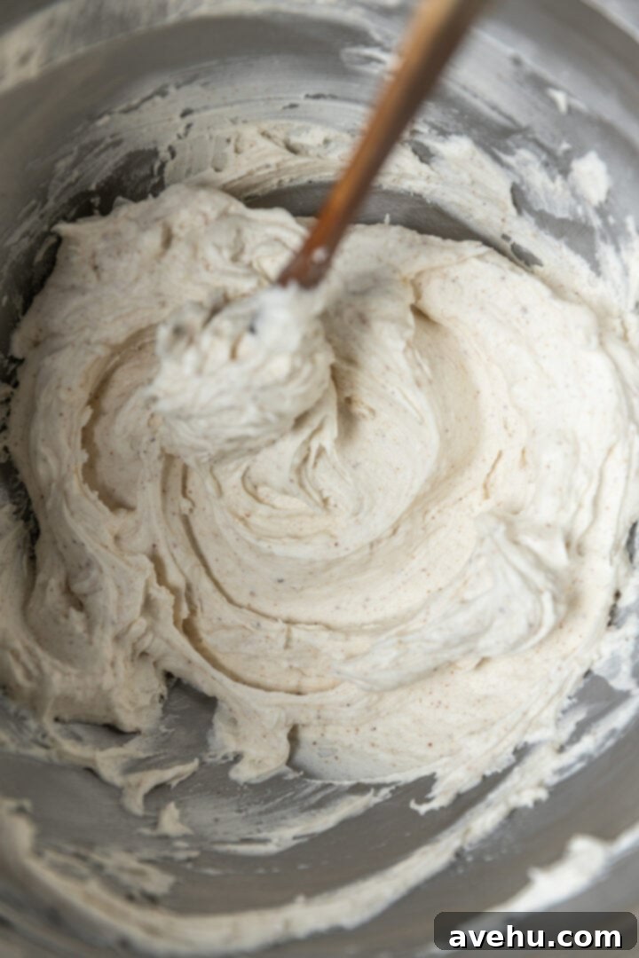 Your Ultimate Brown Butter Frosting 10 Smooth, fluffy brown butter frosting in a mixing bowl with a spatula, indicating perfect consistency.