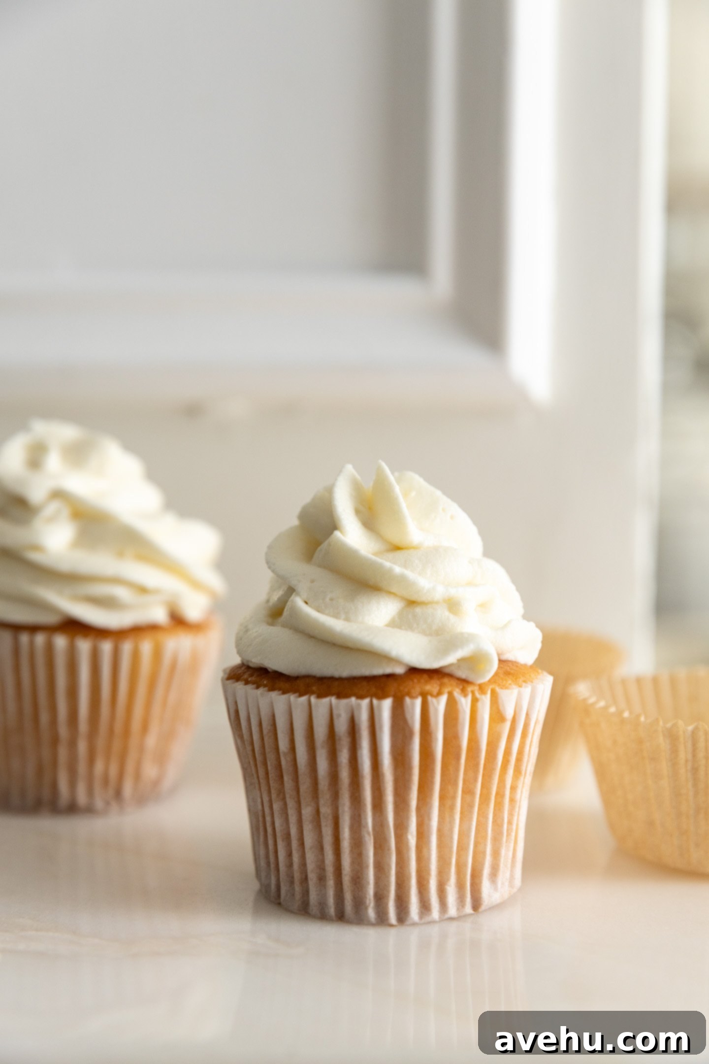 Effortless Cream Cheese Frosting No Powdered Sugar 2 Stable cream cheese frosting made with granulated sugar, beautifully piped onto a vanilla cupcake, showcasing its smooth texture.