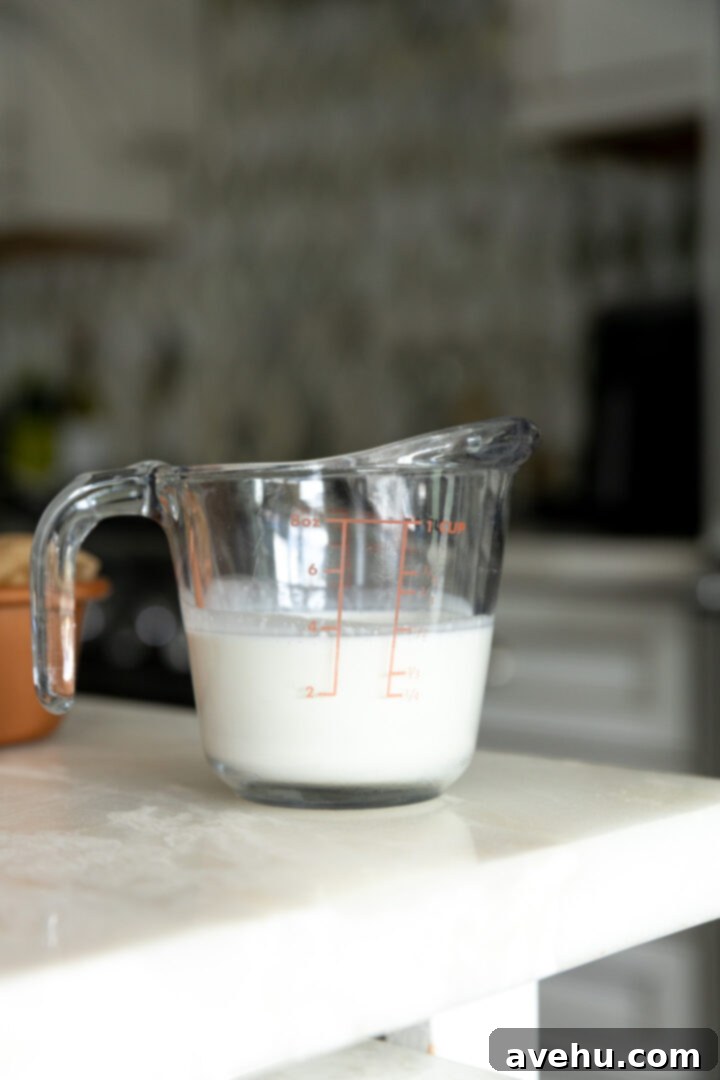 Effortless Cream Cheese Frosting No Powdered Sugar 7 Fresh heavy whipping cream measured in a cup, ready to be transformed into fluffy whipped cream for stable frosting.