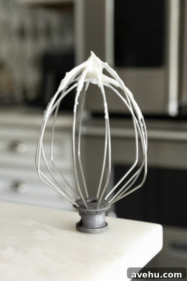 Effortless Cream Cheese Frosting No Powdered Sugar 8 Light and airy homemade whipped cream forming soft peaks on a whisk attachment, prepared for folding into the cream cheese frosting.