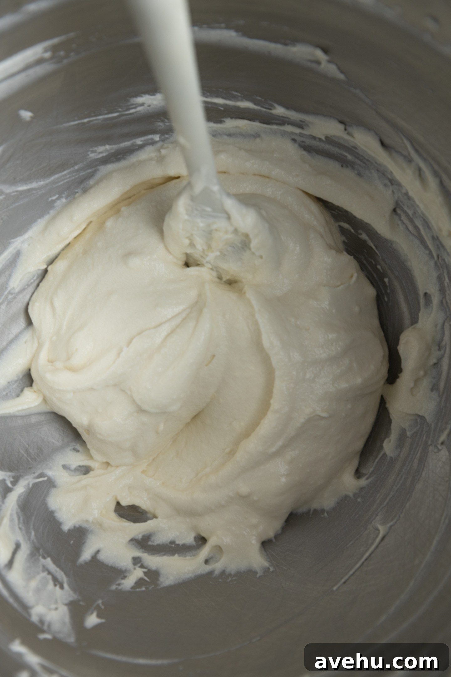 Effortless Cream Cheese Frosting No Powdered Sugar 9 The final, pipeable cream cheese frosting without powdered sugar, now enriched with whipped cream, showing a significantly thicker and bulkier texture in the mixing bowl.
