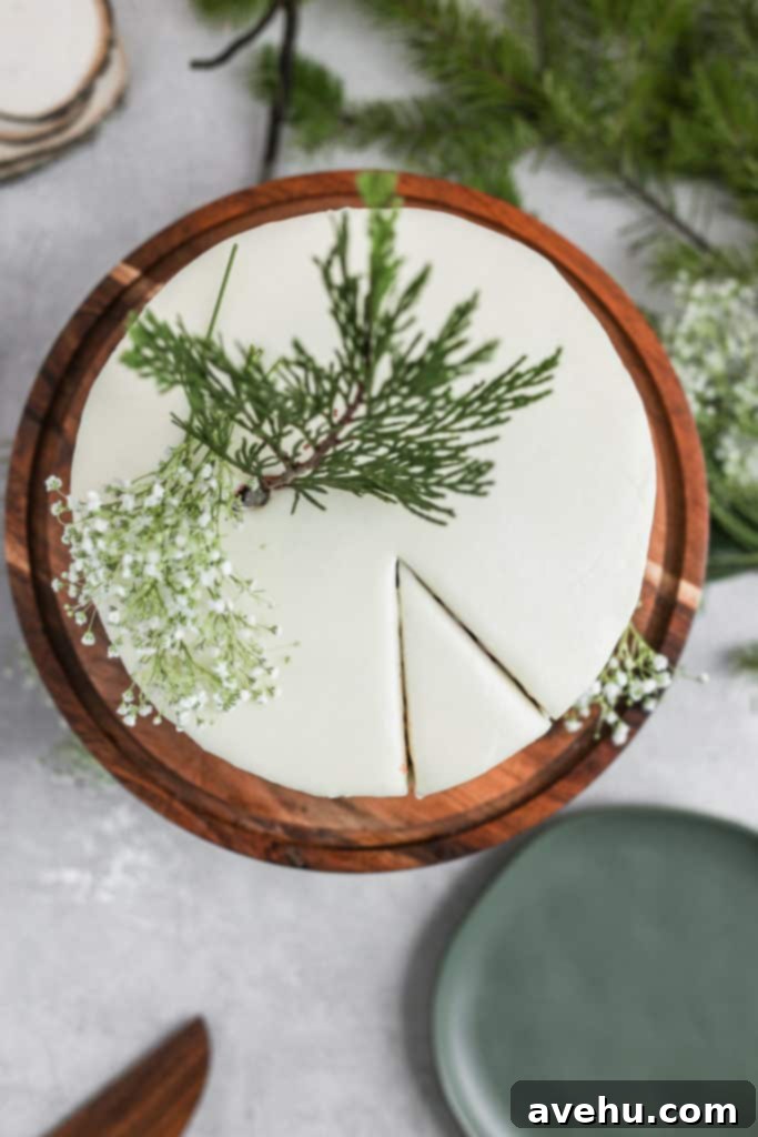 Effortless Rich Red Velvet Cake 4 Cream cheese frosted easy red velvet cake decorated with leaves on a wood cake stand on a gray background.