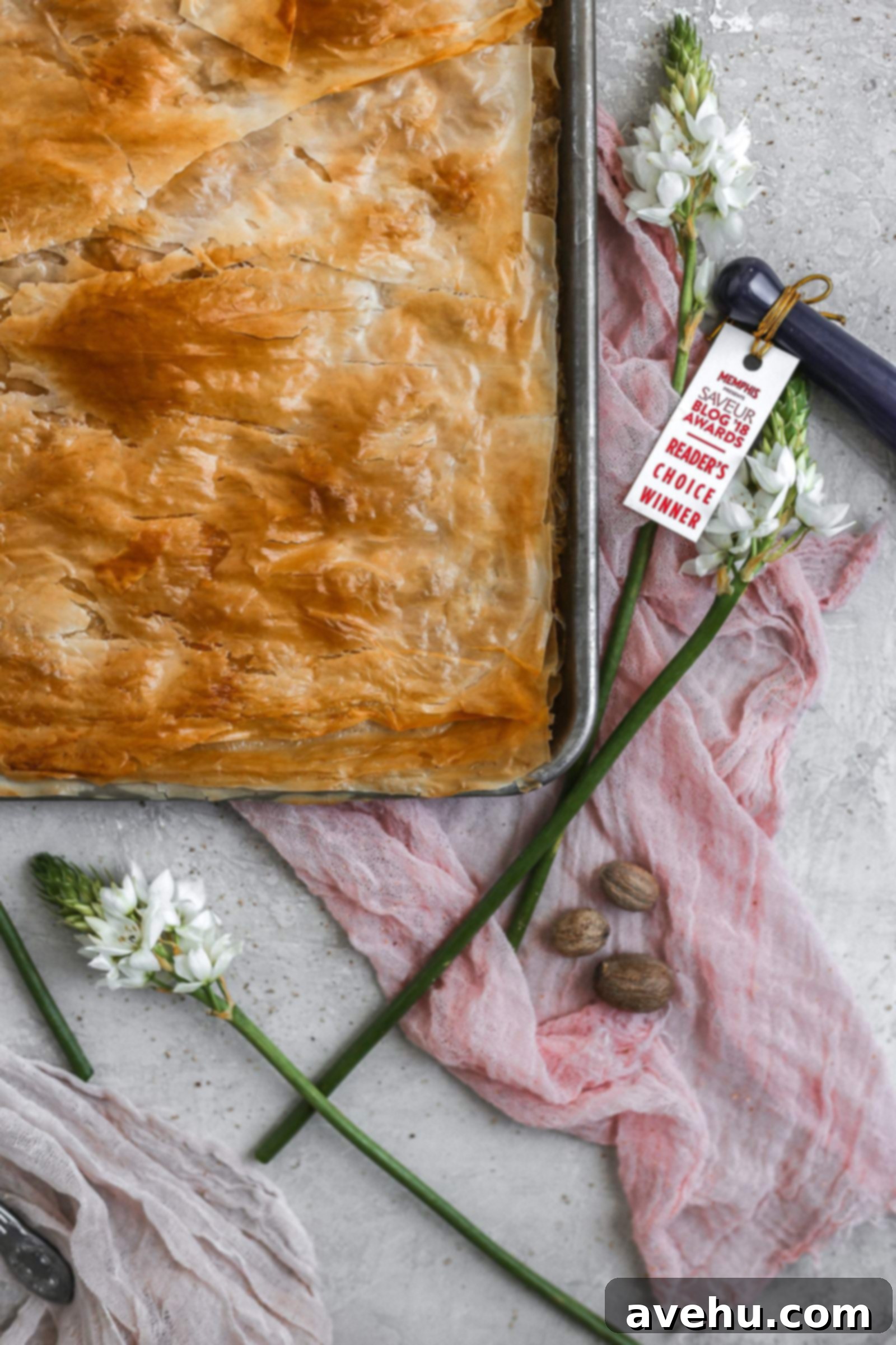 2018 Saveur Blog Awards Peach Slab Pie 5 The corner of a peach slab pie in a sheet pan styled on pink cheesecloth and flowers.