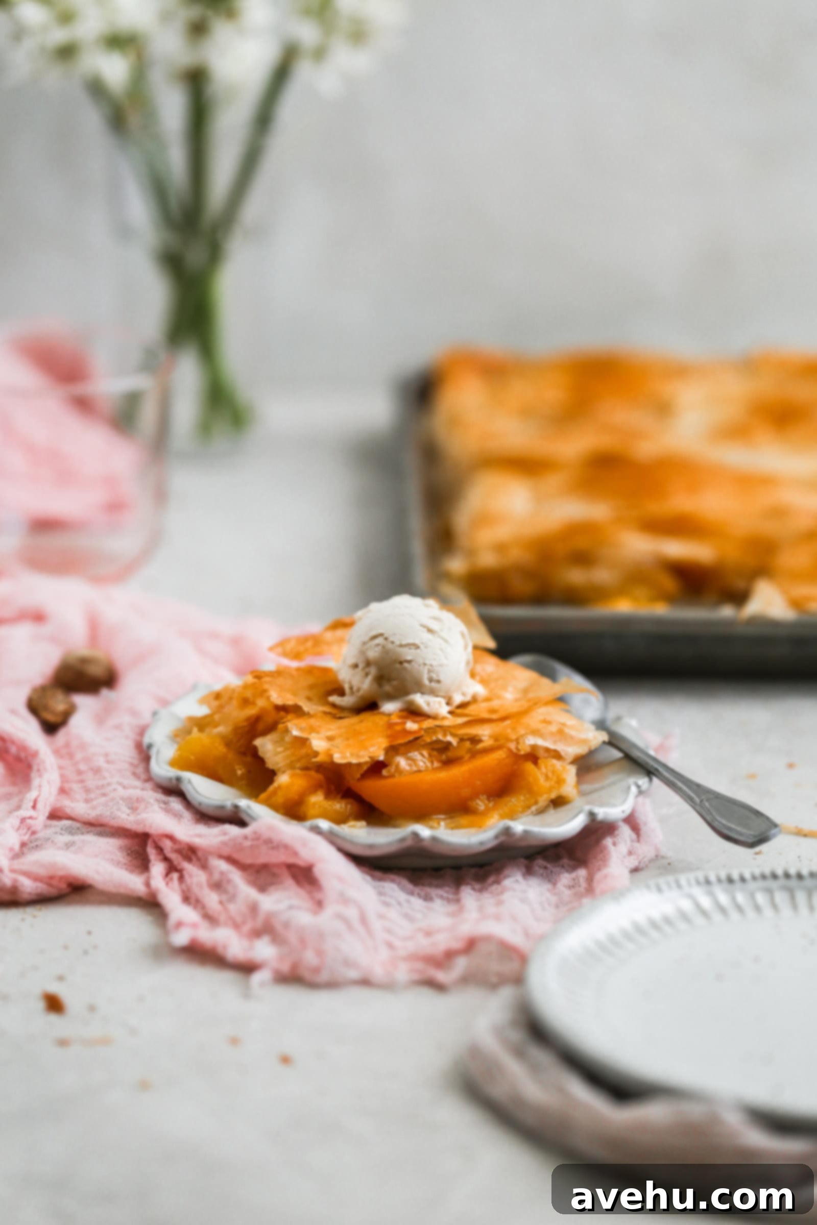 2018 Saveur Blog Awards Peach Slab Pie 7 A piece of peach slab pie on a gray plate topped with ice cream.