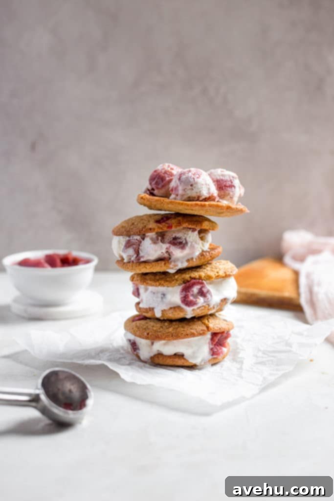Tangy-Sweet Rhubarb Strawberry Ice Cream Sandwiches 4 A stack of three rhubarb ice cream sandwiches on a white surface, showcasing the vibrant red filling.
