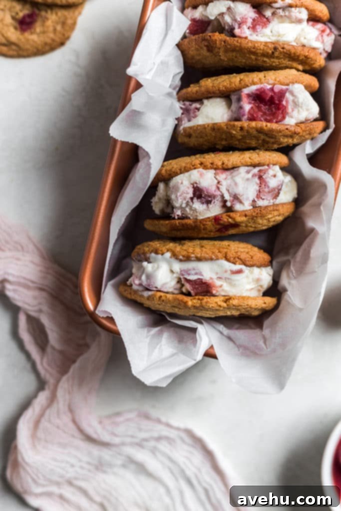 Tangy-Sweet Rhubarb Strawberry Ice Cream Sandwiches 7 Rhubarb ice cream sandwiches neatly arranged on their sides in a white loaf pan, separated by small parchment paper squares.