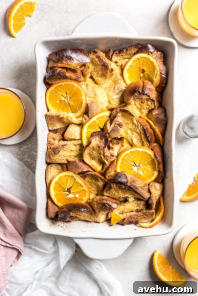 Overnight Golden Challah French Toast Bake 3 challah pieces in a large dish with orange slices on top
