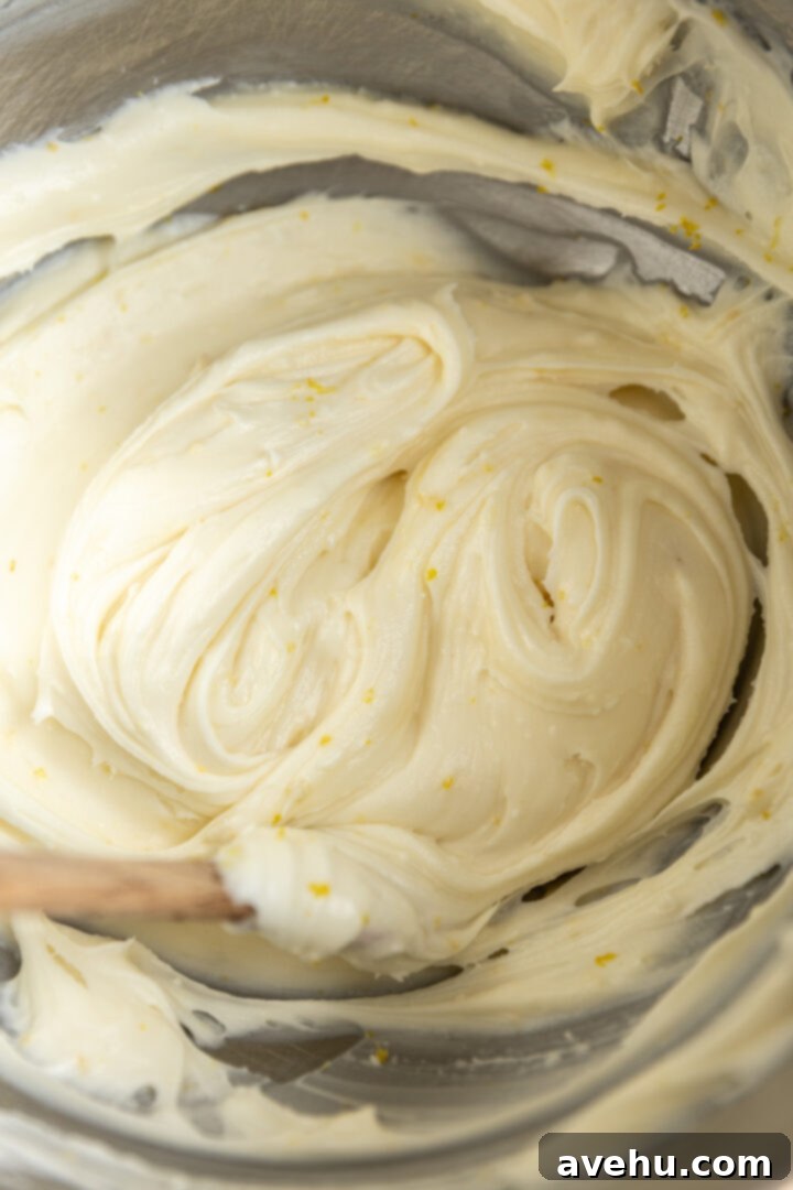 Sunshine Lemon Poppyseed Yogurt Layer Cake 11 Smooth, fluffy lemon cream cheese frosting in a mixing bowl, ready for assembly.