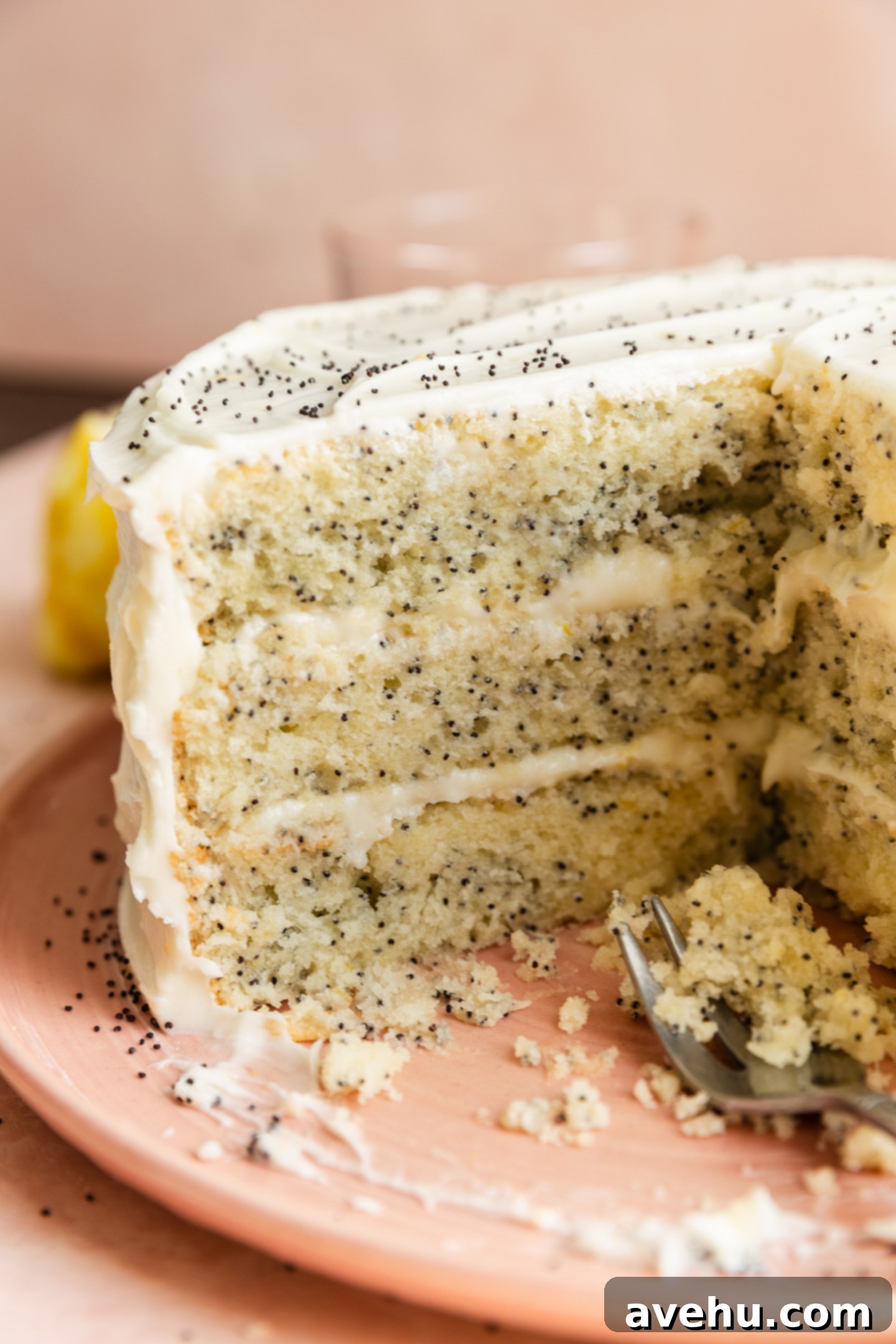 Sunshine Lemon Poppyseed Yogurt Layer Cake 13 A close-up view of the interior of a three-layer lemon poppy seed cake, showing its fluffy texture and frosting layers.