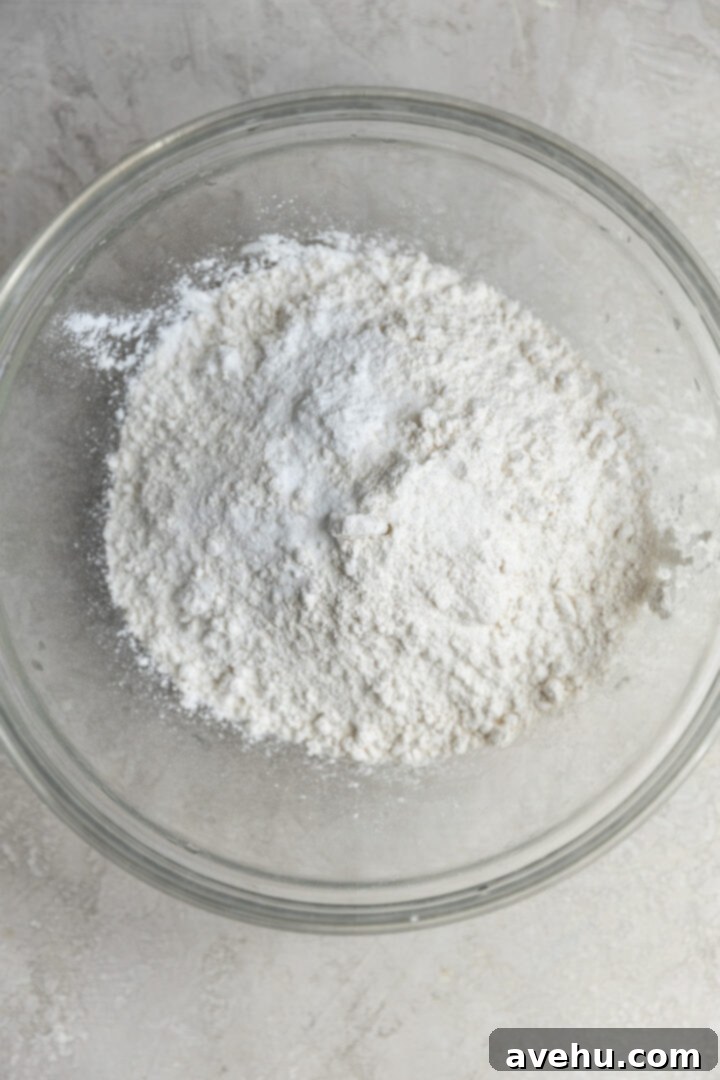 Sunshine Lemon Poppyseed Yogurt Layer Cake 4 Dry ingredients for lemon poppy seed cake, including flour, baking powder, baking soda, and salt, combined in a bowl.