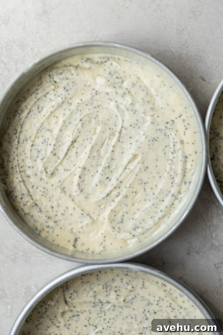 Sunshine Lemon Poppyseed Yogurt Layer Cake 8 Smooth lemon poppy seed cake batter evenly distributed into a 9" round cake pan, ready for baking.
