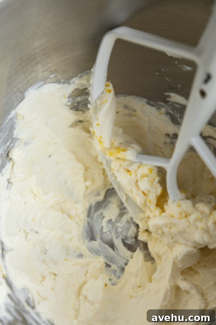 Sunshine Lemon Poppyseed Yogurt Layer Cake 10 Softened cream cheese, butter, and lemon zest being creamed together in a mixer bowl.
