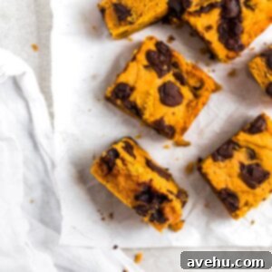 Pumpkin Chocolate Chunk Delights 6 Close-up of freshly baked pumpkin bars with rich chocolate chunks, beautifully arranged on parchment paper for a fall dessert.