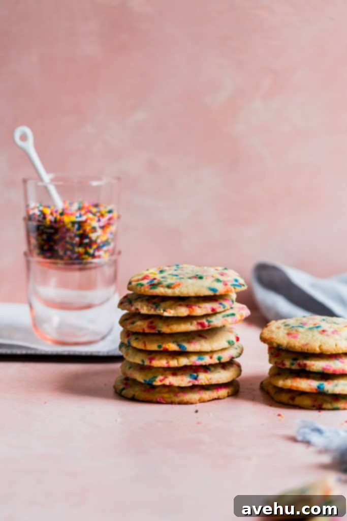 Scratch Baked Funfetti Delights 8 A vibrant close-up of baked funfetti cookies stacked on a pink background, showcasing their colorful sprinkles