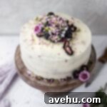Effortless and Perfectly Moist Blackberry Cake 16 The top of a white cake with blackberries and flowers.