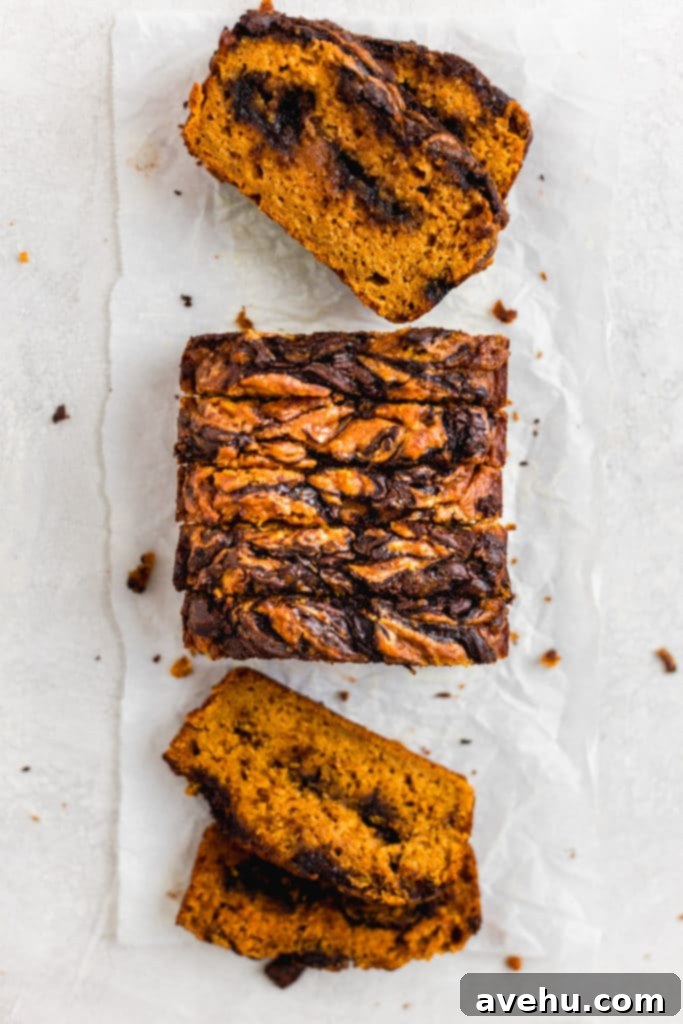 Decadent Chocolate Chip Pumpkin Bread 4 Slices of pumpkin bread with chocolate lined up on a white surface.