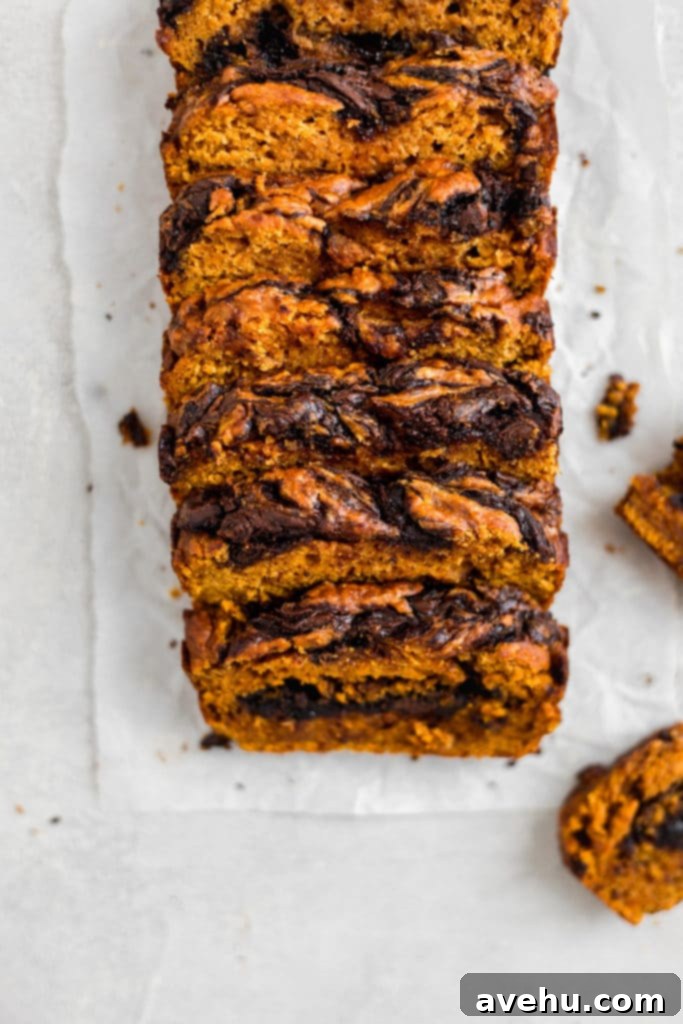 Decadent Chocolate Chip Pumpkin Bread 6 A chocolate pumpkin loaf sliced and put back together on a white surface.