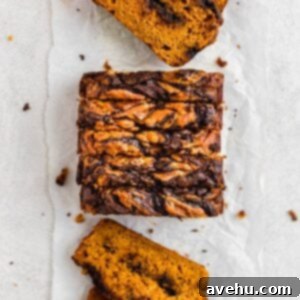 Decadent Chocolate Chip Pumpkin Bread 7 Slices of pumpkin bread with chocolate lined up on a white surface.